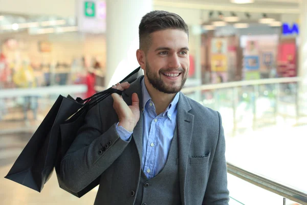 Pohledný muž v obleku s nákupní tašky. — Stock fotografie