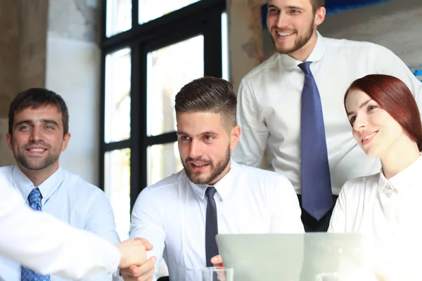 Welkom bij ons team. Jonge moderne zakenlieden schudden de handen terwijl ze werken in het creatieve kantoor. — Stockfoto