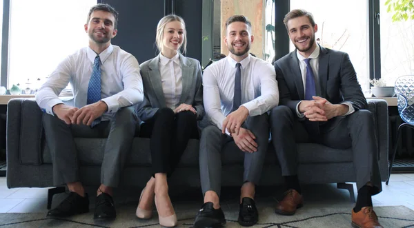 Skupina čtyř obchodních lidí sedícího na pohovce. My jsme tým, kterého potřebujete, pokud chcete uspět. — Stock fotografie