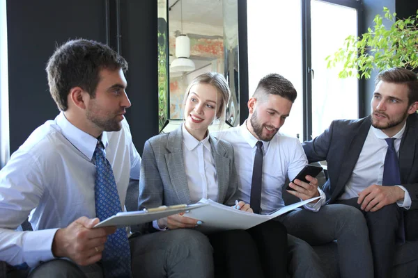 Grupo de cuatro personas de negocios sentadas en un sofá. No podrían estar más felices de trabajar juntos. . —  Fotos de Stock