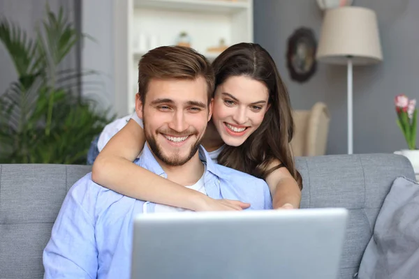 Jong paar doet wat online winkelen thuis, met behulp van een laptop op de Bank. — Stockfoto
