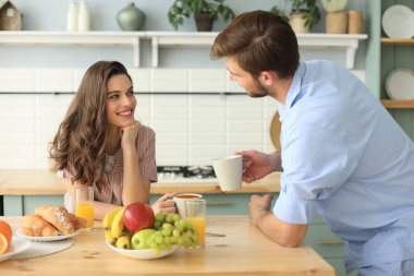 Pijamalı güzel bir çift evde yemek pişirirken birbirlerine bakıp gülümsüyor..