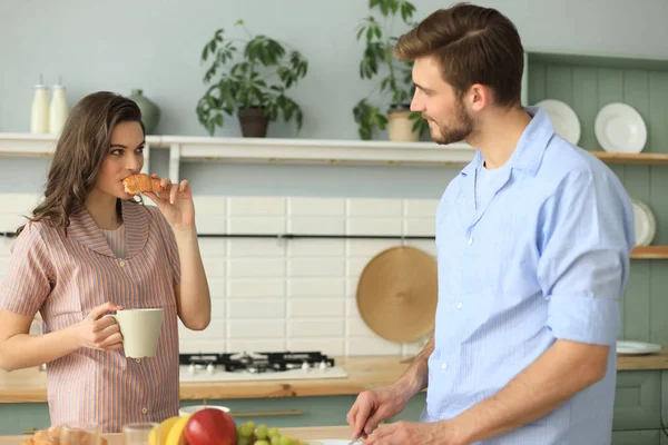 Όμορφο νεαρό ζευγάρι με πιτζάμες κοιτάζει ο ένας τον άλλο και χαμογελώντας ενώ το μαγείρεμα στην κουζίνα στο σπίτι. — Φωτογραφία Αρχείου