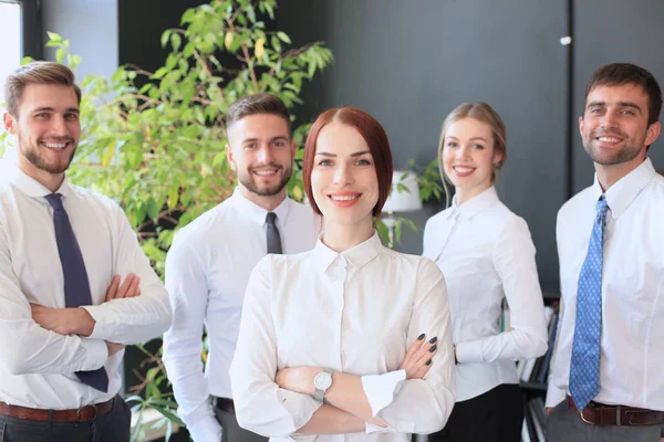 Gelukkig jonge zakenvrouw staande voor haar team. — Stockfoto