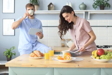 Evde sabah portakal suyu içme, mutfakta birlikte pişirme pijama mutlu genç çift portresi.