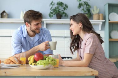 Pijamalı güzel bir çift evde yemek pişirirken birbirlerine bakıp gülümsüyor..