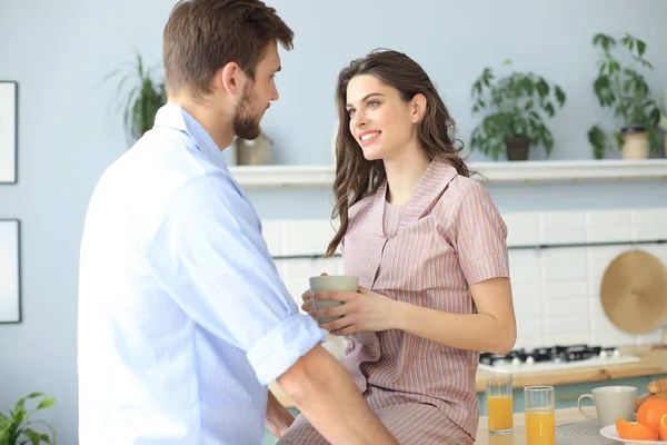 Hermosa pareja joven en pijama se mira y sonríe mientras cocina en casa. —  Fotos de Stock