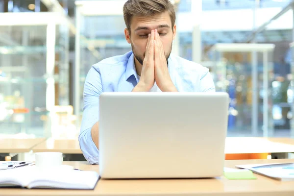 Porträtt av en ung man som sitter vid sitt skrivbord på kontoret. — Stockfoto