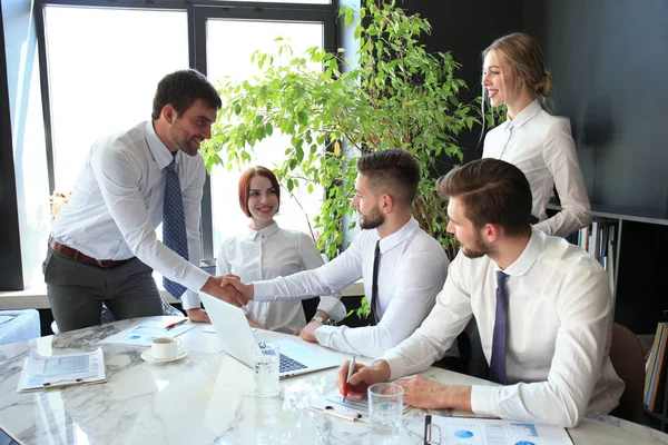Empresário apertando as mãos para selar um acordo com seu parceiro e colegas no escritório . — Fotografia de Stock