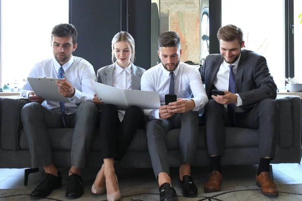 Groep van vier zakelijke mensen zittend op de Bank. Ze kunnen niet gelukkiger zijn over samenwerken. — Stockfoto