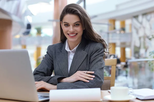 Portrait d'une jeune femme d'affaires joyeuse assise à la table au bureau et regardant la caméra. — Photo