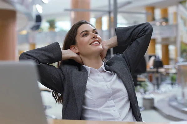 Młoda bizneswoman siedzi w biurze trzymać ręce za głowę relaks czuje się dobrze. — Zdjęcie stockowe