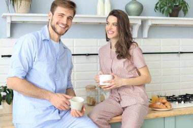 Evde sabah portakal suyu içme, mutfakta birlikte pişirme pijama mutlu genç çift portresi.