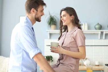 Pijamalı güzel bir çift evde yemek pişirirken birbirlerine bakıp gülümsüyor..