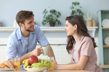 Pijamalı güzel bir çift evde yemek pişirirken birbirlerine bakıp gülümsüyor..
