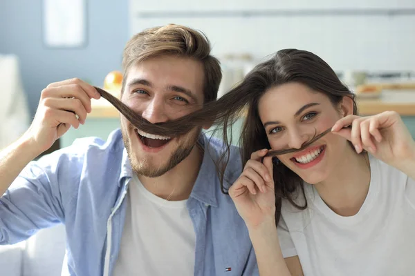 Portret van schattige jonge speelse paar plagen met nep snor zittend in de Bank. — Stockfoto