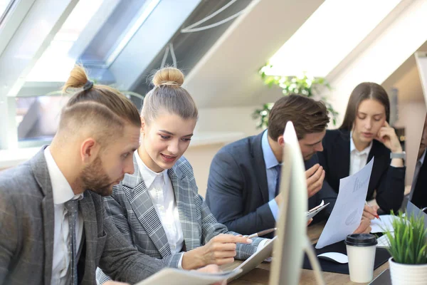 Groupe de jeunes gens d'affaires travaillant, communiquant assis au bureau avec leurs collègues . — Photo