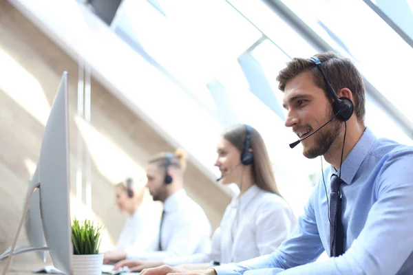 Portret van callcenter medewerker vergezeld door zijn team. Lachende klant support operator aan het werk. — Stockfoto