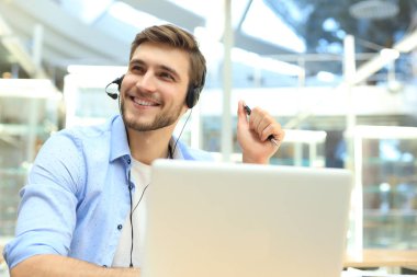 Gülümseyen yakışıklı genç erkek çağrı merkezi operatörü.