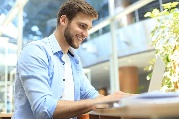 Porträtt av en ung man som sitter vid sitt skrivbord på kontoret. — Stockfoto