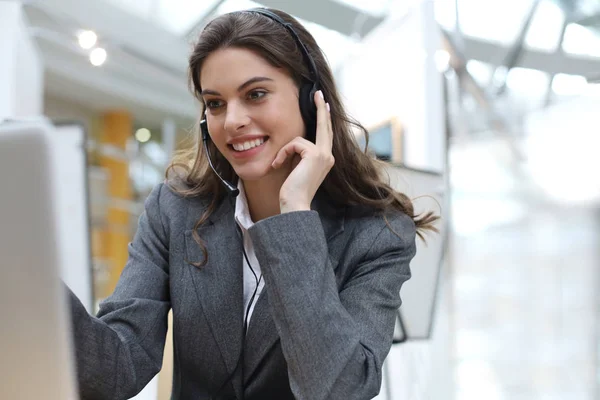 Operadora de suporte ao cliente feminina com fone de ouvido e sorrindo. — Fotografia de Stock