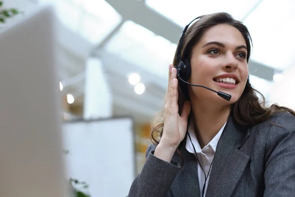 Operadora de suporte ao cliente feminina com fone de ouvido e sorrindo. — Fotografia de Stock