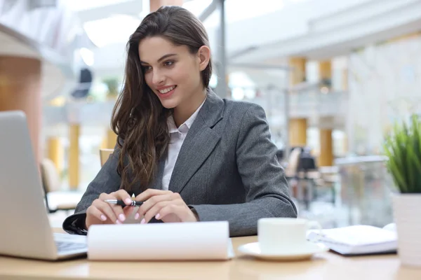 Portrait d'une jeune femme d'affaires brune utilisant un ordinateur portable au bureau. — Photo