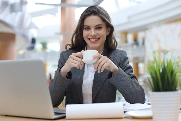 Belle femme d'affaires souriante assise dans le bureau avec une tasse de café . — Photo