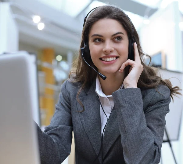 Operadora de suporte ao cliente feminina com fone de ouvido e sorrindo. — Fotografia de Stock