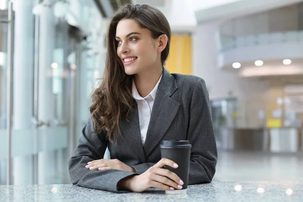 Belle femme d'affaires souriante debout dans le bureau avec une tasse de café . — Photo