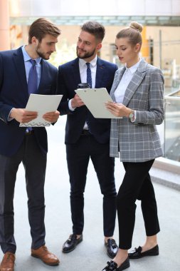 Ofis toplantısında iş görüşmesi ne zaman ayakta duran üç genç işadamı.