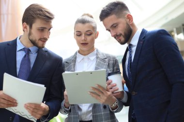 Ofis toplantısında iş görüşmesi ne zaman ayakta duran üç genç işadamı.