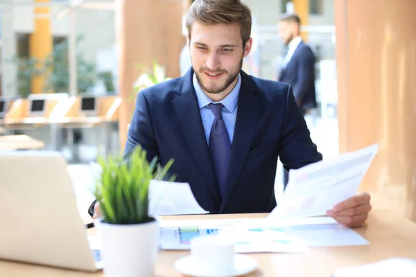 Porträt eines jungen Mannes, der an seinem Schreibtisch im Büro sitzt. — Stockfoto