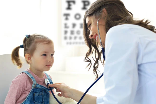 Little girl at the doctor for a checkup. Doctor woman auscultate the heartbeat of the child.