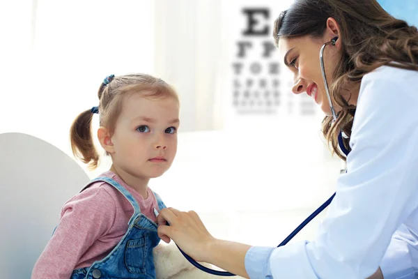 Una ragazzina dal dottore per un controllo. Medico donna auscultare il battito cardiaco del bambino. — Foto Stock