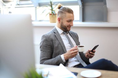 İş adamı ofisteki cep telefonunu kullanıyor..