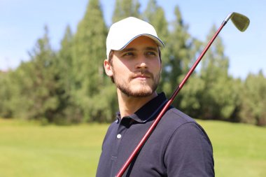 Adam güzel güneşli yeşil golf sahasında golf oynuyor.
