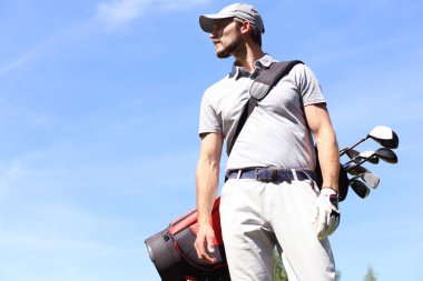Golf oyuncusu yaz golfü sırasında yolda yürüyor ve çanta taşıyor..
