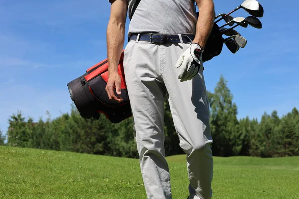 Oříznutý obrázek mužského golfisty nesoucího golfový vak s řidiči při chůzi po zelené trávě. — Stock fotografie