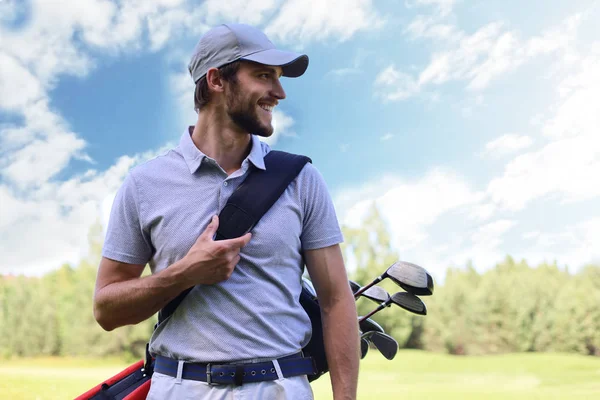 Portrét mužského golfisty nesoucího golfový vak při chůzi po zelené trávě golfové hole. — Stock fotografie