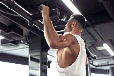 Fit ve kaslı adam bir spor salonunda yatay bar üzerinde çekerek.