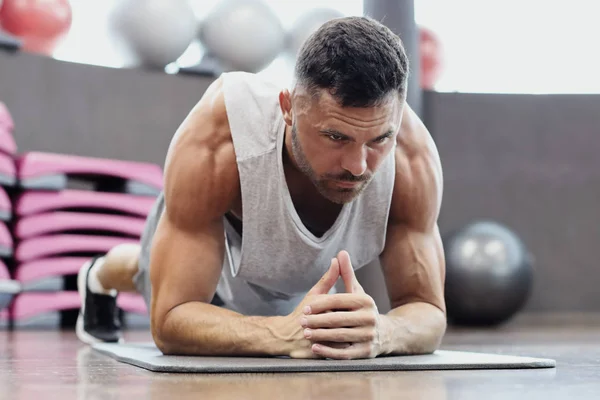 Portret mężczyzny fitness robi szalunki ćwiczeń w siłowni. — Zdjęcie stockowe