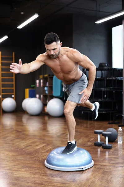 Apto atleta realizando exercício na ginástica hemisfério bosu bola no ginásio . — Fotografia de Stock