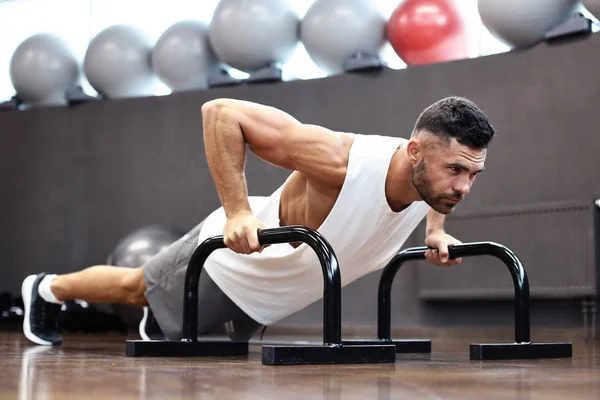 Вмістити і м'язистий чоловік робить горизонтальні штовхання з брусками в спортзалі . — стокове фото