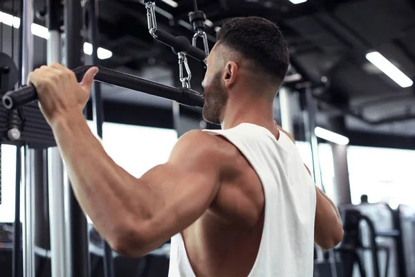 Fit and muscular man shakes his back on the simulator. Back view. — Stock Photo, Image