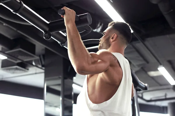 Dopasowanie i muskularny Człowiek ciągnąc się na poziomym barze w siłowni. — Zdjęcie stockowe
