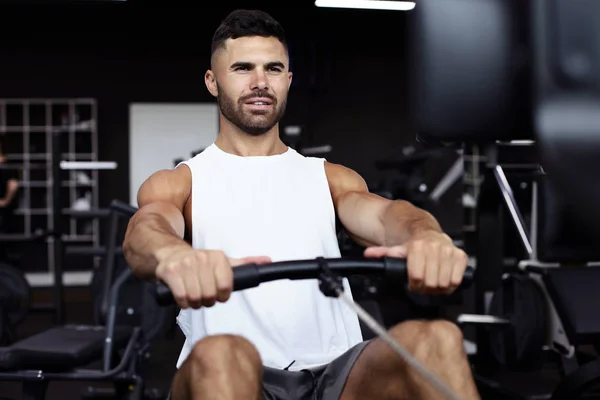 Fitter und muskulöser Mann mit Rudergerät im Fitnessstudio. — Stockfoto