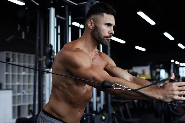Fit i muskularny Człowiek trenuje mięśnie piersiowe na symulatorze bloku w siłowni. — Zdjęcie stockowe