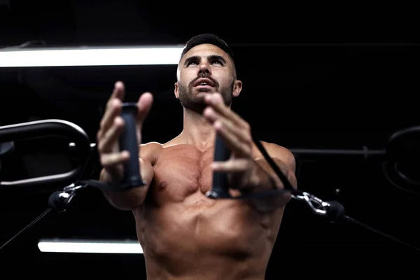 Fitter und muskulöser Mann trainiert Brustmuskulatur im Blocksimulator in der Turnhalle. — Stockfoto