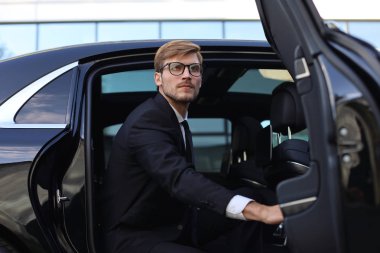 Yakışıklı ciddi genç işadamı onun rahat yeni araba içine oturan ve ofise gidiyor.